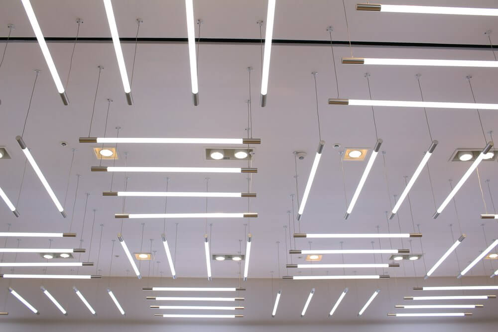 Ceiling with modern linear light fixtures evenly spaced in a grid pattern, illuminating the area with bright white light.