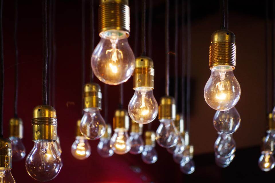Hanging light bulbs with brass fittings against a dark background, some lit and others unlit.