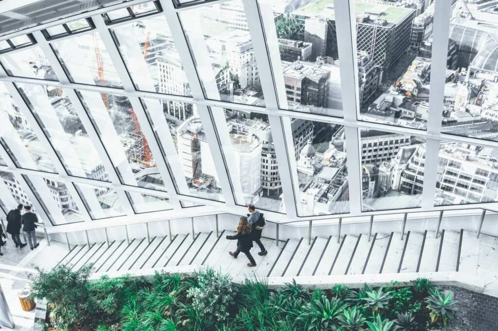 People walking down stairs in a modern building with large windows overlooking a cityscape.
