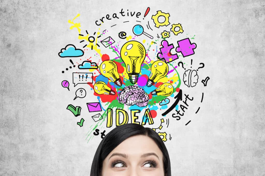 Person looking up at colorful doodles of light bulbs, clouds, gears, and the word "IDEA" on a gray background.