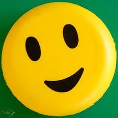 A round yellow smiley face with black eyes and mouth on a green background.