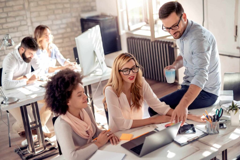 Five members of a team working in an office with three of them collaborating