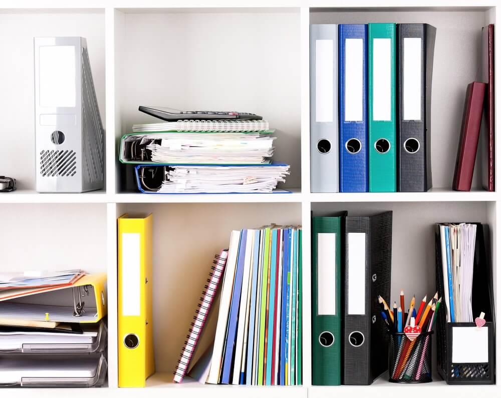Shelves with binders, documents, notebooks, and office supplies, including pencils and a calculator.