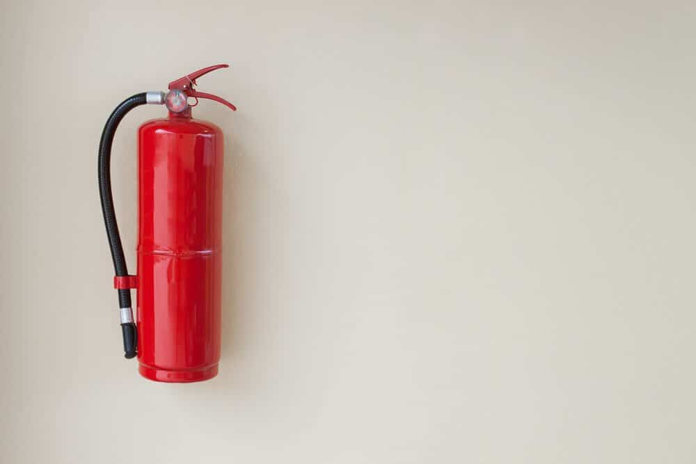 Red fire extinguisher mounted on a light beige wall.